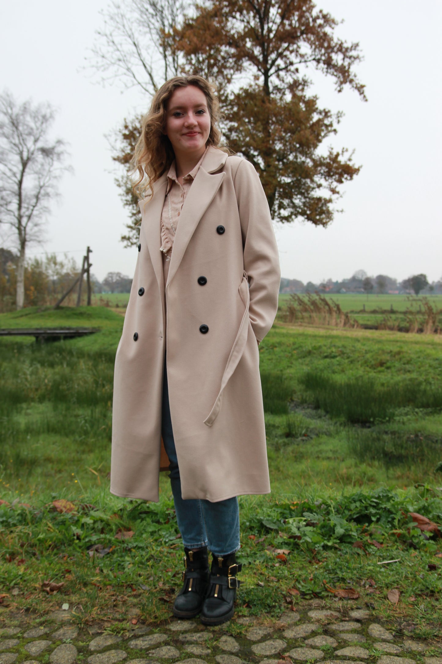 Trendy beige trenchcoat met brede kraag en scheve zakken aan de voorkant