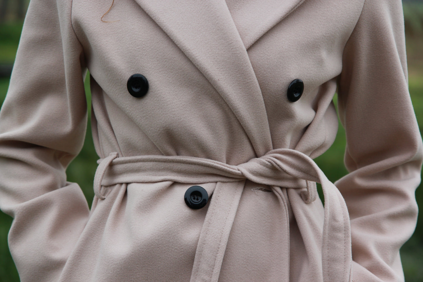 Detailopname van de knopen en tailleriem van de beige trenchcoat