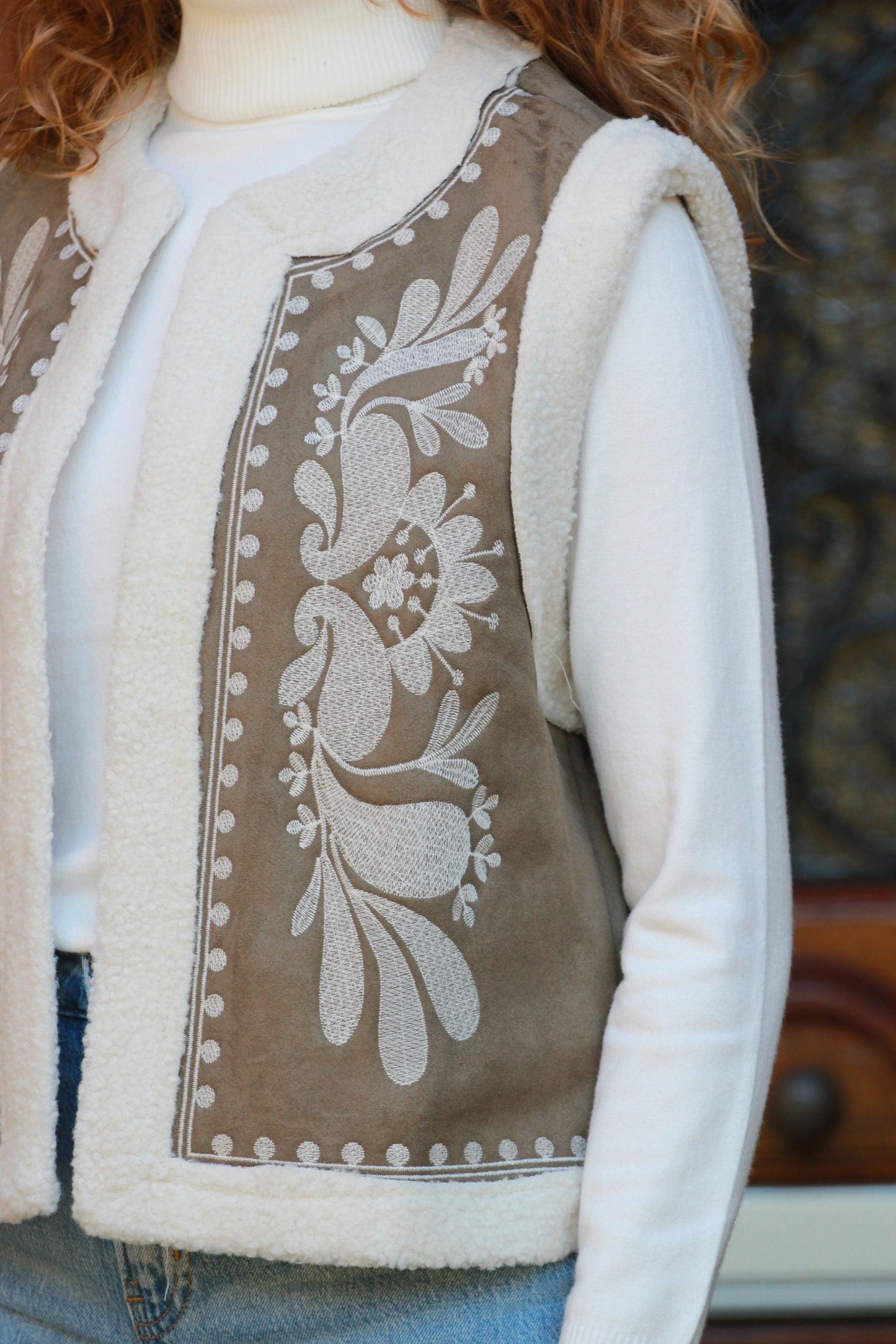 Close-up van groen gilet Cloé met geborduurde bloemen en teddy voering